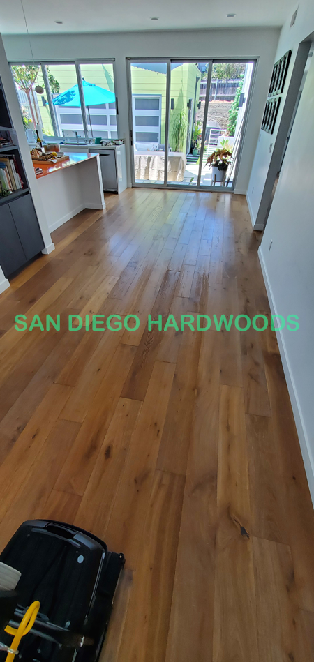 Professional hardwood floor deep cleaning in San Diego using a Bona PowerScrubber to remove dirt and grime from wire-brushed oak flooring before re-coating. Our process safely deep cleans wood grain better than steam cleaning or standard mopping used by companies like Stanley Steemer or Zerorez.